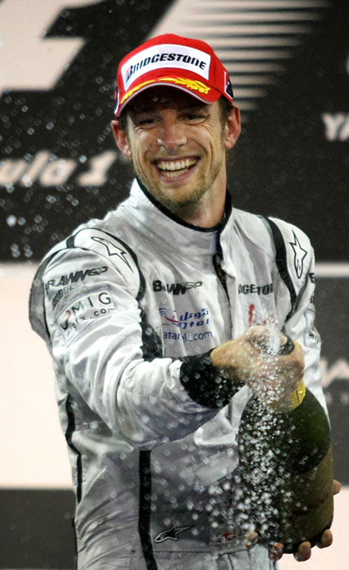 Jenson Button celebrates after finishing third in the final race of the season