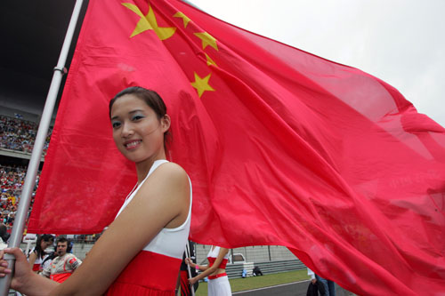 A grid girl waves a Chinese flag on the grid