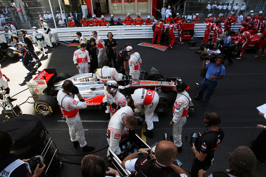 Jenson Button's McLaren is serviced on the grid during the red flag period