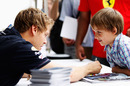 Sebastian Vettel signs his autograph for a young fan