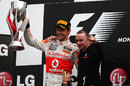 Jenson Button celebrates his remarkable victory on the podium with Paddy Lowe
