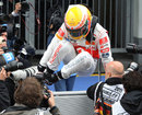 Lewis Hamilton leaps the fence to celebrate with his team in parc ferme