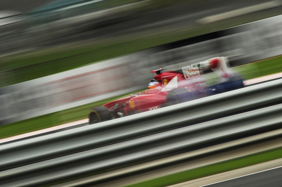 Fernando Alonso flashes past the guardrails in his Ferrari