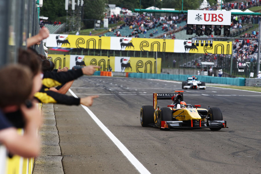 Romain Grosjean crosses the line to take victory and celebrates in front of his DAMS team