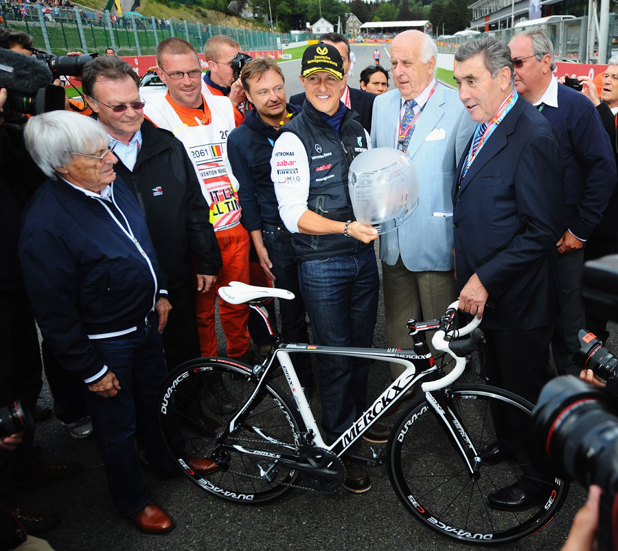 Michael Schumacher is presented with a road bike by cycling legend Eddy Merckx on the 20th anniversary of his GP debut