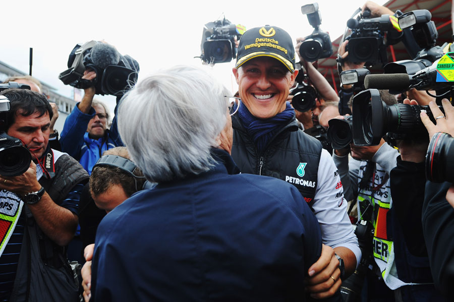 Michael Schumacher is greeted by Bernie Ecclestone on the 20th anniversary of his GP debut