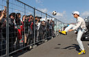 Nico Rosberg plays football over the fence of the paddock before the first practice session