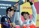 Race winner Jenson Button soaks championship winner Sebastian Vettel on the podium