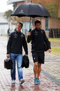 Michael Schumacher keeps dry under an umbrella as he arrives at the circuit on Friday morning