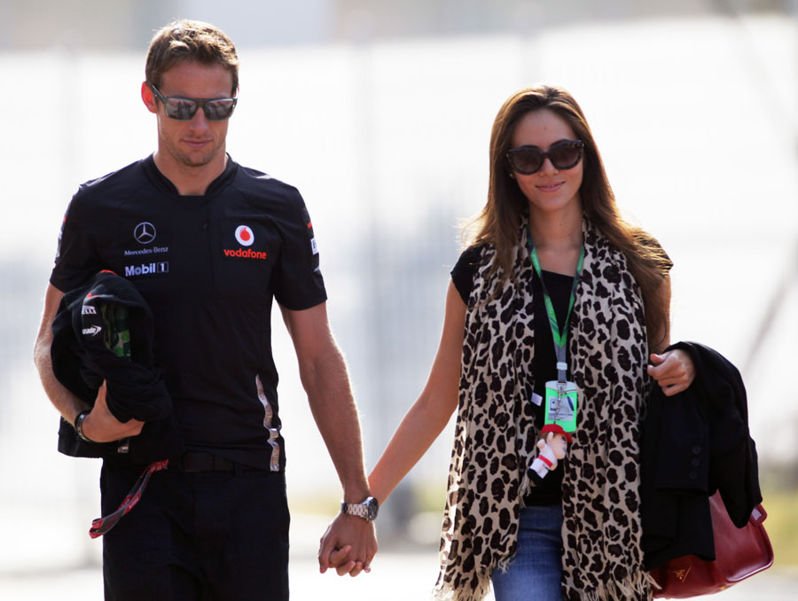 Jenson Button and Jessica Michibata walk through the paddock