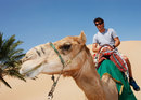 Mark Webber rides a camel on a Sand Dune Safari