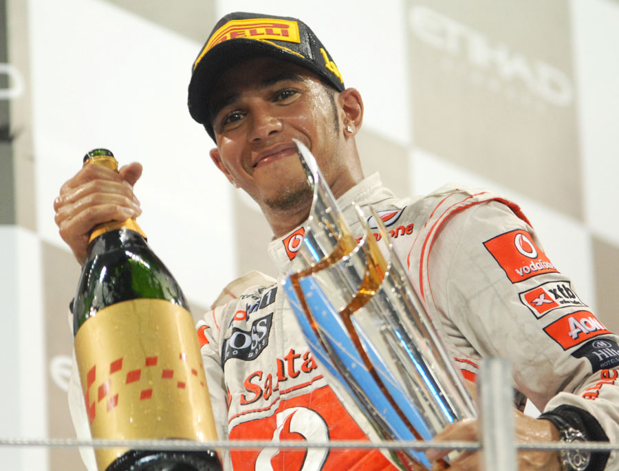 Lewis Hamilton celebrates with rose water and his trophy on the podium