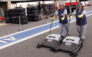 Workers clean the pit lane surface as the teams set up
