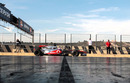 Jenson Button passes an empty garage in the pit lane