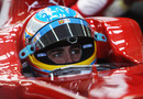Fernando Alonso sits in his cockpit in the Ferrari garage