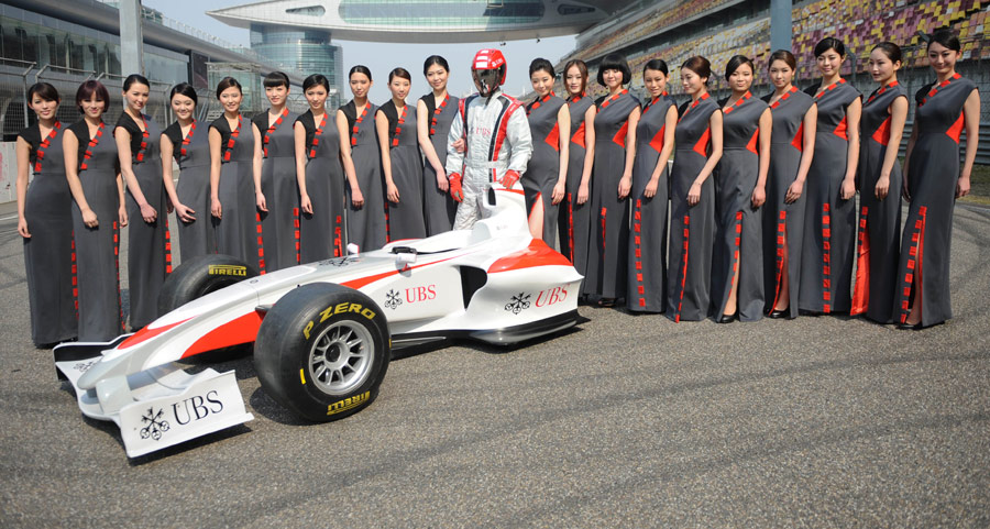 Chinese models pose with an F1 show car during a launch show for the 2012 Chinese Grand Prix