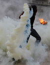A Bahraini anti-government protester throws a tear gas canister fired by riot police back toward them