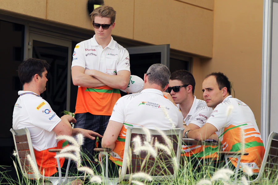 Nico Hulkenberg and Paul di Resta chat with team members in the paddock