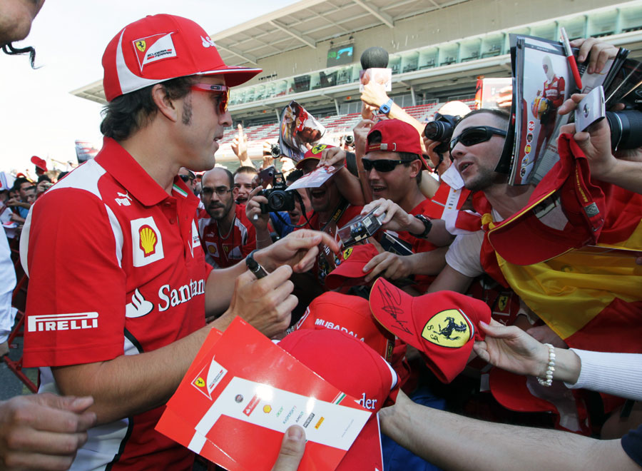 Fernando Alonso signs autographs for fans in the pit lane