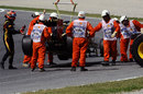 Romain Grosjean walks away as marshals recover his Lotus in FP3