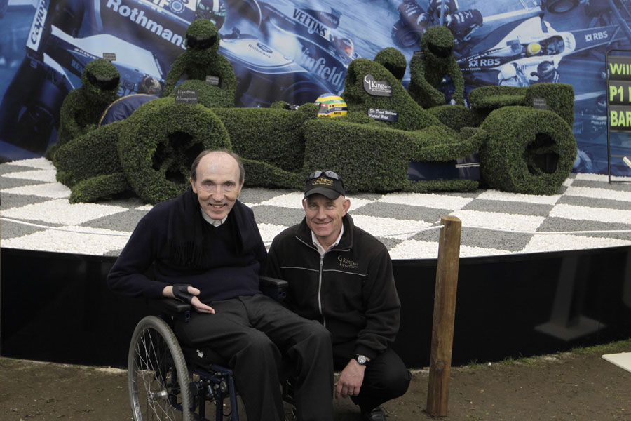 Sir Frank Williams poses in front of a Williams display at the Chelsea Flower Show