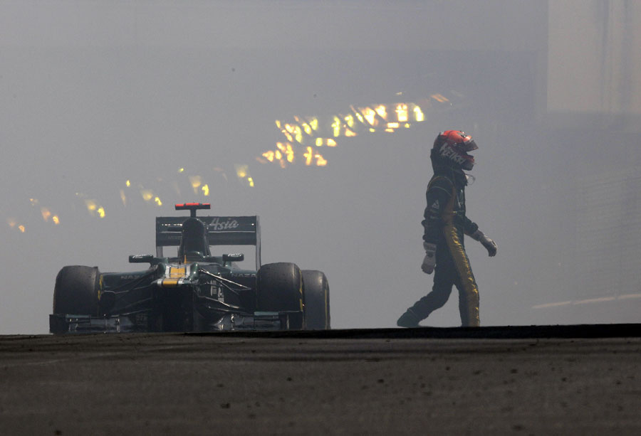 Heikki Kovalainen walks away from his smoking Caterham
