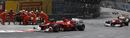 The Ferraris of Fernando Alonso and Felipe Massa pass the stricken Romain Grosjean