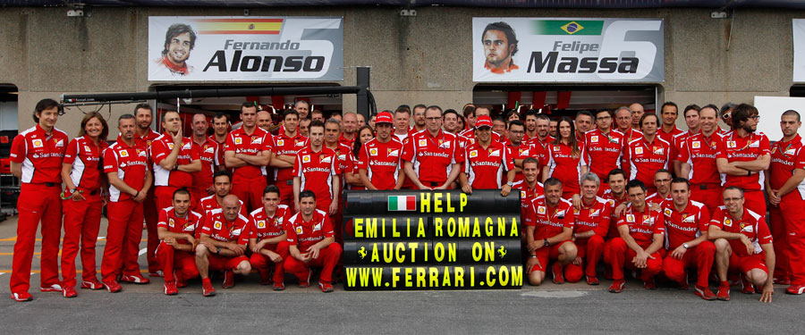 The Ferrari team pose with a banner reading 