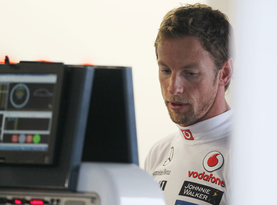 Jenson Button looks at the data in the McLaren garage