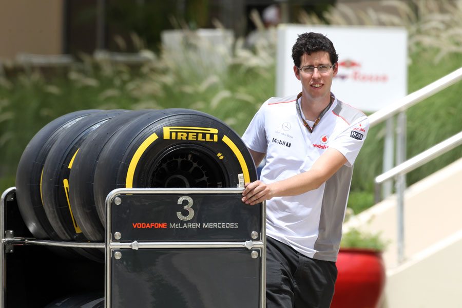 A McLaren mechanic moves tyres through the paddock