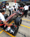 Jenson Button's McLaren is pushed back into the pits