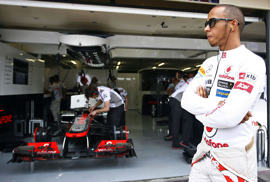 Lewis Hamilton watches on from the front of the McLaren garage