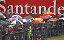 Fans shelter from the rain as they watch practice