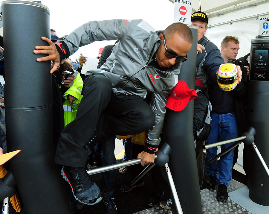 Lewis Hamilton hurdles the barriers on his way into the paddock