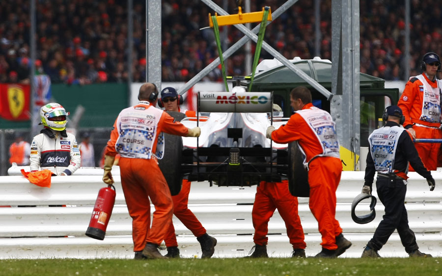 Sergio Perez watches on as his car is recovered following a clash with Pastor Maldonado