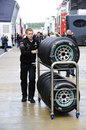 A Mercedes mechanic pushes hard tyres through the wet paddock