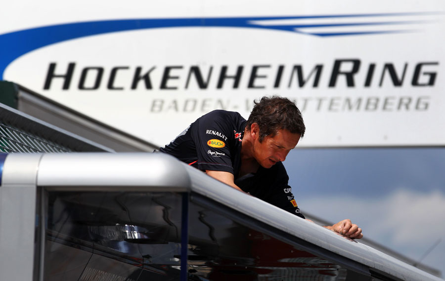 A Red Bull mechanic works on the motorhome in the paddock