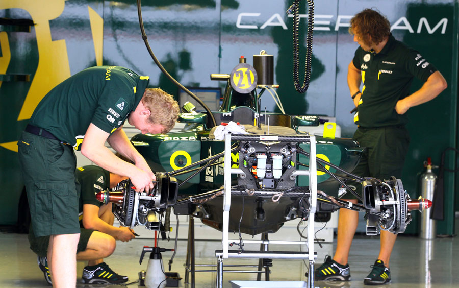 Caterham mechanics work on one of the cars in the garage on Wednesday