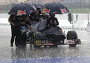 Toro Rosso mechanics get caught in a downpour as they retrieve a car from the weighbridge after FP3