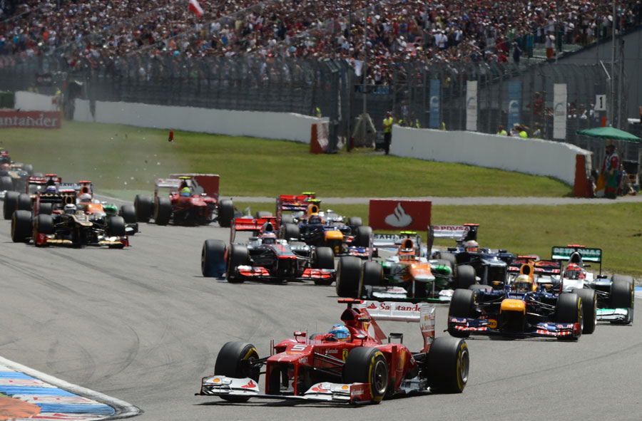 Fernando Alonso leads the field into the first corner as Felipe Massa makes contact in the background