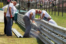 Track workers repair the Armco on the pit straight after an accident in the GP2 race on Sunday morning