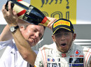 Sam Michael pours champagne down Lewis Hamilton's neck on the podium