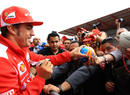 Fernando Alonso signs autographs for the fans in the pit lane