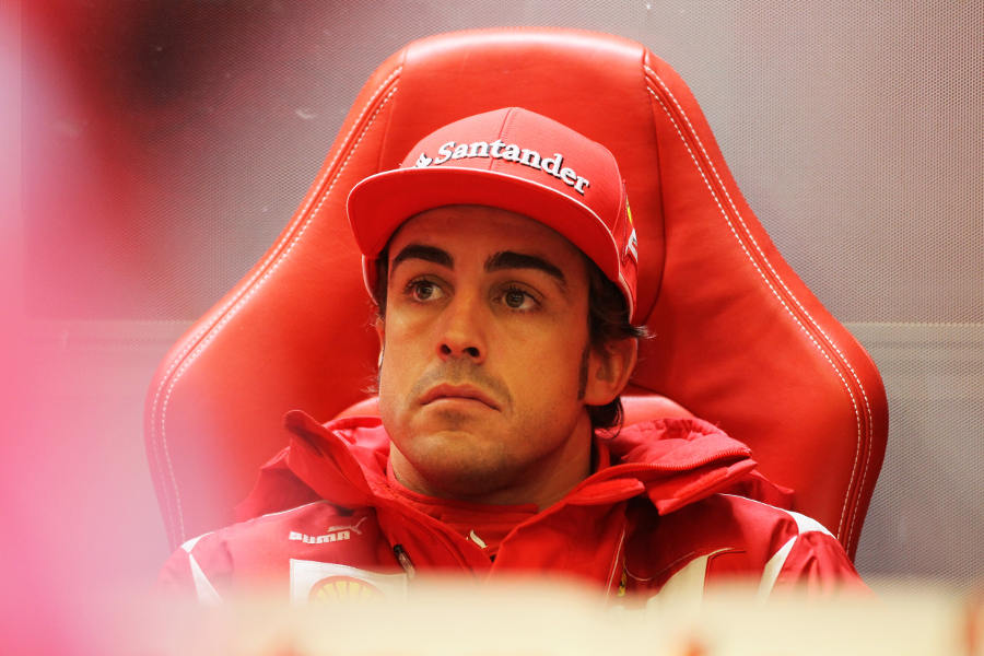 Fernando Alonso watches on from the sanctuary of the Ferrari garage