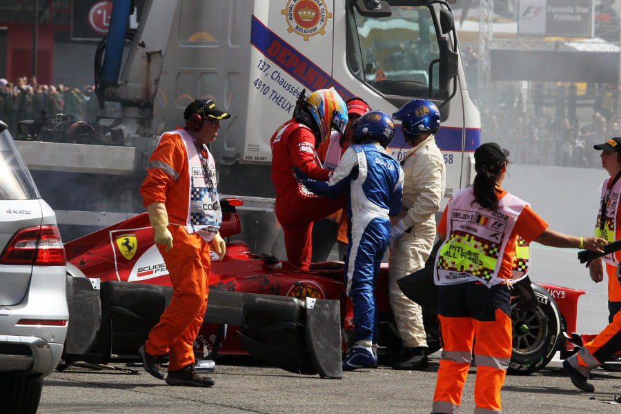 Championship leader Fernando Alonso is helped out of his car after a first corner crash