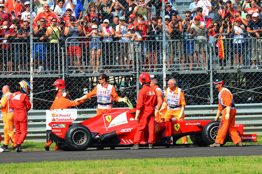 Fernando Alonso looks over his Ferrari after an engine problem
