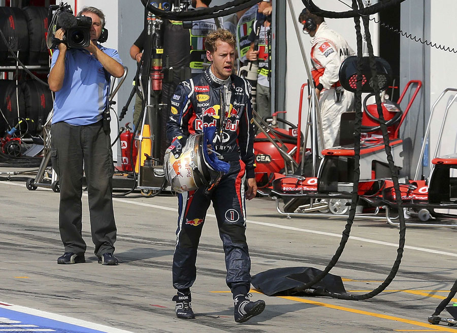 Sebastian Vettel walks back to the Red Bull garage after retiring