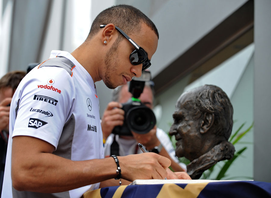 Lewis Hamilton signs a book of condolences for Professor Sid Watkins on race day 