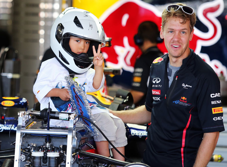 Sebastian Vettel gives a young fan a tour of the Red Bull garage