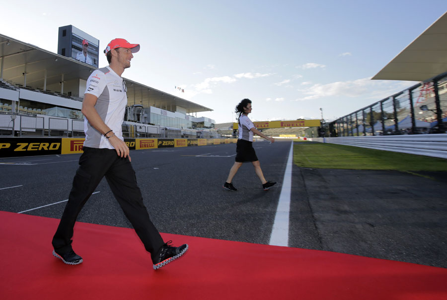 Jenson Button crosses the circuit to greet fans in the main grandstand